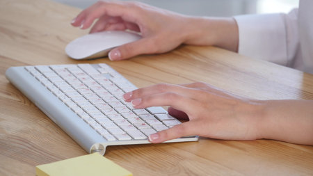 Young woman's hands typing at computer keyboard.の写真素材