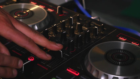 DJ mixes songs on equipment, hands closeup.