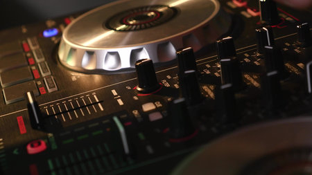 DJ mixes songs on equipment, hands closeup.