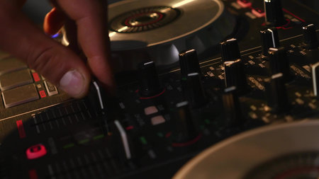 DJ mixes songs on equipment, hands closeup.