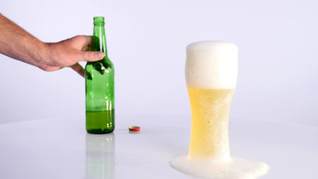 A bottle of beer is poured into a cup on a white background.の写真素材