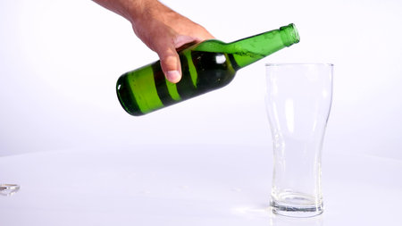 A bottle of beer is poured into a cup on a white background.の写真素材
