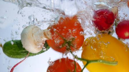 Mixed vegetables stir in the water. Bell pepper, tomatoes, cucumber and radish.の写真素材