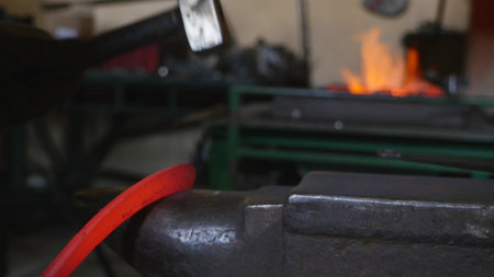 Blacksmith hammering the end of an Iron bar into a hook.