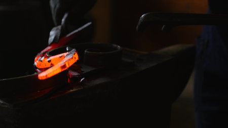 blacksmith working with hot glowing metal, bending steel in a smithery.