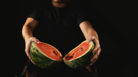 hands cutting watermelon on black background.の写真素材