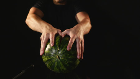 hands cutting watermelon on black background.の写真素材