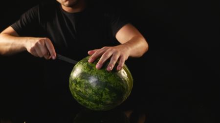 hands cutting watermelon on black background.の写真素材