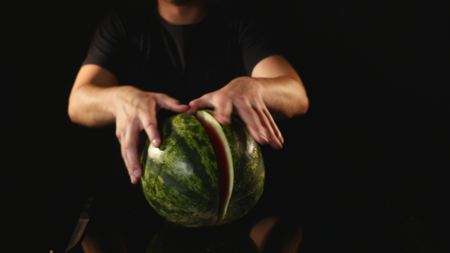 hands cutting watermelon on black background.の写真素材