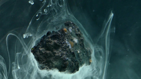 abstract flowing ink in water with stone.