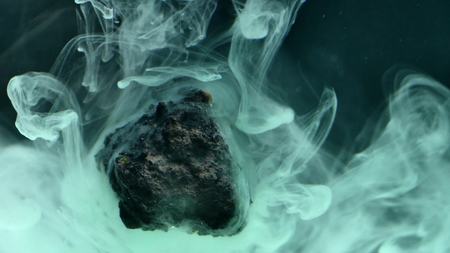 abstract flowing ink in water with stone.の写真素材