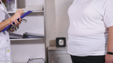 a nutritionist weighs the client and records the indicators in a notebook.の写真素材