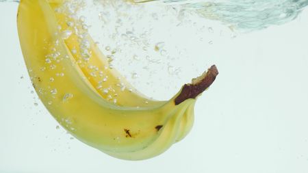 Bananas plunging into water on white background in slow motion.の写真素材