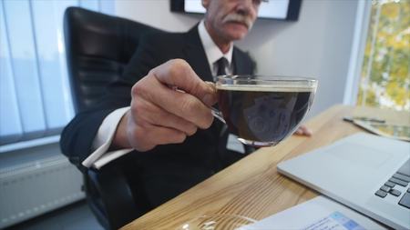 Businessman drinks coffe while watching the laptop screen.の写真素材