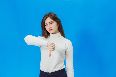 Happy young woman giving thumbs up. A girl on a blue backgroundの写真素材