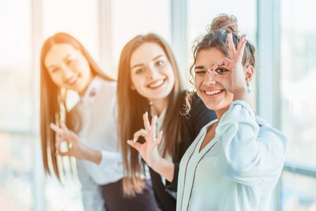 Young pretty business girls show a good gesture. Dressed in classic clothes, smiling copy spaceの写真素材