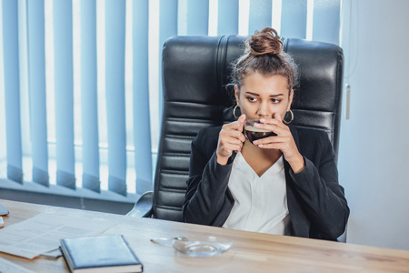 Young business lady works in the office. Close-up of a girl sitting at a table with a laptop while working in coffee time.の写真素材