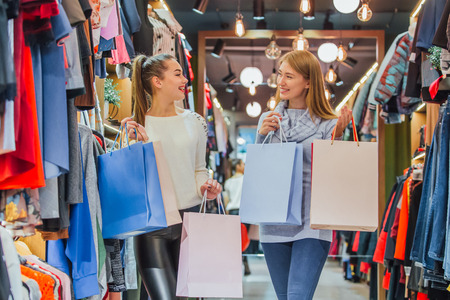 Happy women with shopping bags in the store. During this, they rejoice in it and smileの写真素材