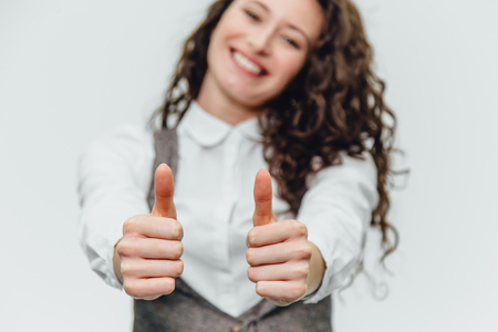 Young business lady with beautiful curly hair on a white background rejoices. During this, the gesture class shows,cope spaceの写真素材