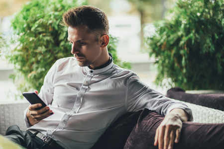 Young businessman texting on a smartphone in street cafeの写真素材