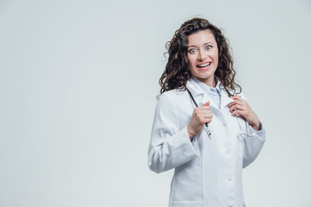 A serious young female Caucasian woman in a laboratory robe, looking at you and holding the...