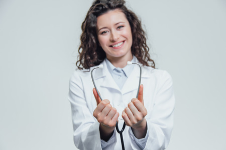 A hand with a stethoscope, the face of the doctor in the background. Close-up concept of medical examination.の写真素材