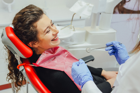Woman at the reception of a dentist in a dental clinic. She sits in a red chair. Happy patient and dentist conceptの写真素材