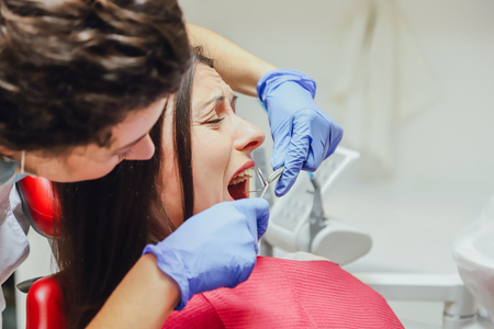 A young woman is shocked by the fear of dental instruments that she looks at her, wide-open eyes. The notion of fear of a dentist and dental treatment.の写真素材