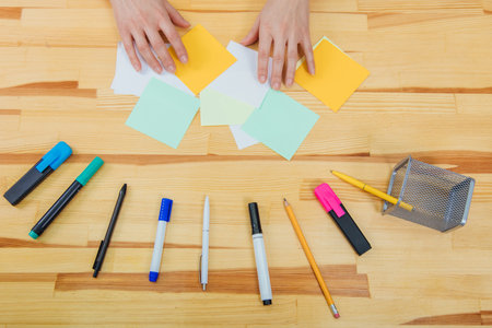 A wooden table in the office. It has a laptop, a pen, markers, pencils. Top view with copy space.