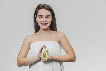 Portrait gorgeous girl in white towel with half avocado. Girl smiles.の写真素材