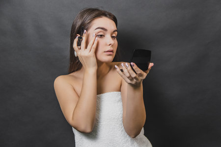 Beautiful young girl on a black background close up. The use of carcasses for eyelashes, the beauty of the face, the clean skin that looks in the mirror, make up the concept.の写真素材