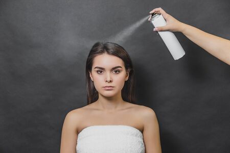 Beauty portrait of young girl with perfect nude make-up. Someone sprinkling hairspray on her loose hair.の写真素材