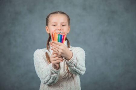 Cute schoolgirl with plaits holding colorful pencilsの写真素材