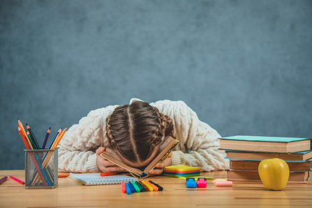 Schoolgirl is with her face on the book looks tired of studying . Tired girl wants to sleep and...