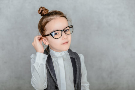 Close up of a small business lady on a gray background. During this In the glasses. Look into the...