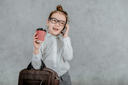 Young businesswoman, baby from a bag and a cup of coffee, isolated on a gray background.