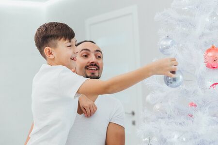 Dad and son decorate a christmas tree togetherの写真素材