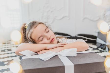 Sweet girl with ponytail is sleeping on big Christmas present, looking amazing.の写真素材