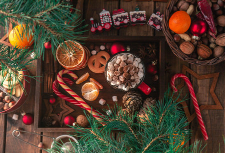 In a wooden tray there is a red mug with marshmallows and New Year's attributesの写真素材