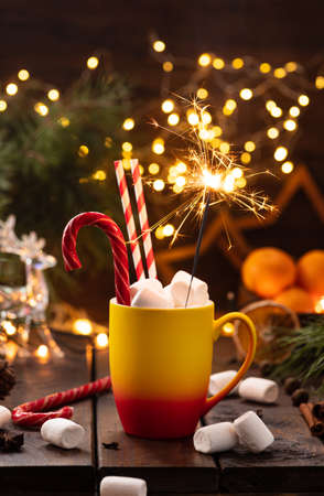 A mug of cocoa with marshmallows from which straws stick out, a caramel stickの写真素材