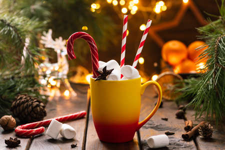 A mug of cocoa with marshmallows from which straws stick out, a caramel stickの写真素材