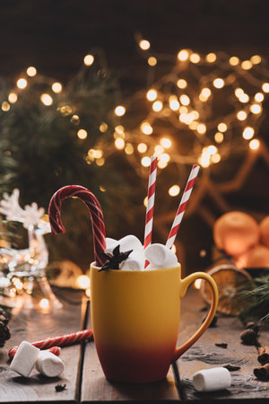 A mug of cocoa with marshmallows from which straws stick out, a caramel stickの写真素材