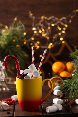 A mug of cocoa with marshmallows from which straws stick out, a caramel stickの写真素材