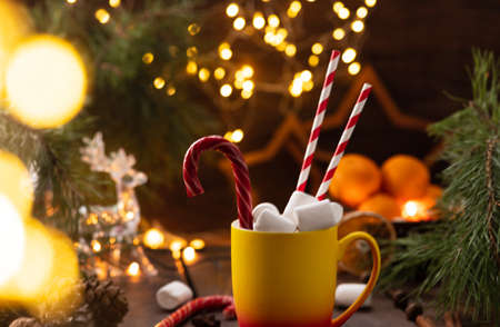 A mug of cocoa with marshmallows from which straws stick out, a caramel stickの写真素材