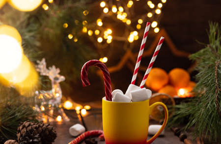 A mug of cocoa with marshmallows from which straws stick out, a caramel stickの写真素材