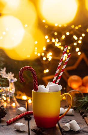 A mug of cocoa with marshmallows from which straws stick out, a caramel stickの写真素材