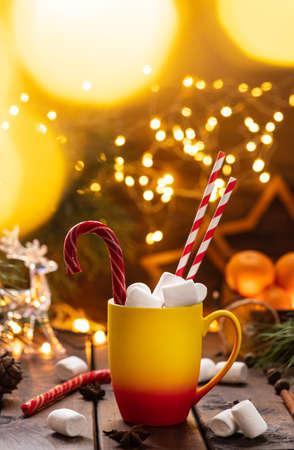 A mug of cocoa with marshmallows from which straws stick out, a caramel stickの写真素材