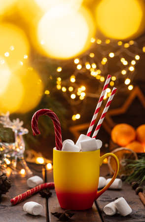 A mug of cocoa with marshmallows from which straws stick out, a caramel stickの写真素材