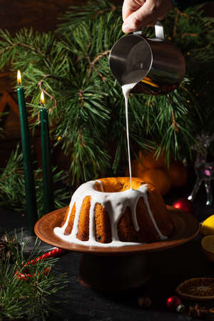 a round cupcake on a dark background is poured from a saucepan with icing on topの写真素材