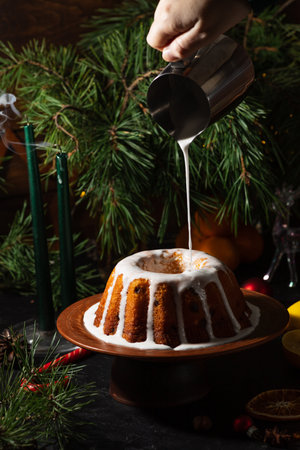 a round cupcake on a dark background is poured from a saucepan with icing on topの写真素材